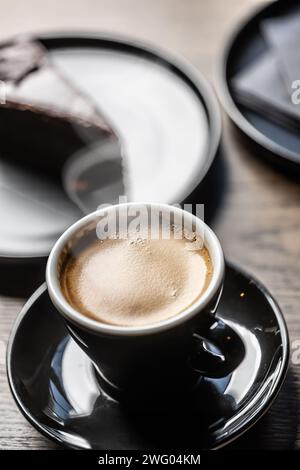 Traditional espresso coffee in a black cup on a table in a cafe. Stock Photo