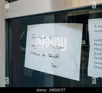 A handwritten closure notice for security measures posted on a storefront window in the city. Stock Photo