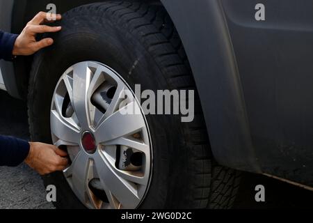 Man installing tire with thumb resting under wheel Stock Photo