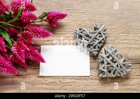 Pink celosia, paper card and two wicker hearts on wooden background, copy space Stock Photo