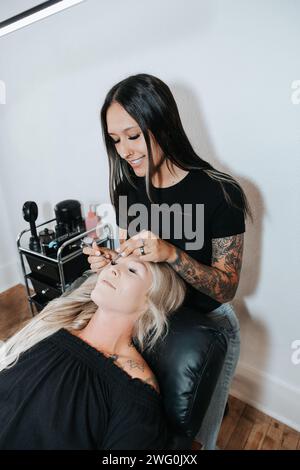 Stylish girl applies lashes, client beauty in relaxation Stock Photo