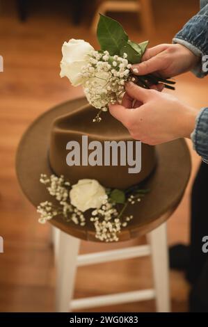 High angle of person's hands holding flowers to put on a brown hat Stock Photo