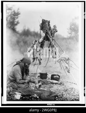 A Sarsi kitchen, c1927. Sarsi woman cooking over campfire, Alberta, Canada. Stock Photo