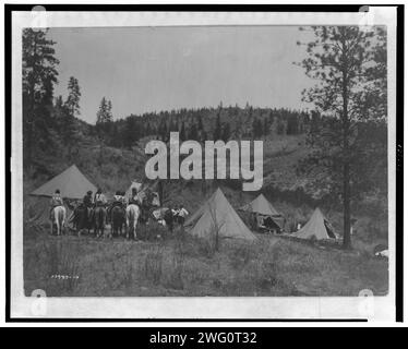 Author's camp among the Spokan, c1910. Five tents erected in a clearing, Edward S. Curtis in center, Spokane men and women on horseback on the left. Stock Photo