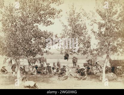 Dinner scene, between 1887 and 1892. Cowboys eating dinner, seated on the ground under trees. Stock Photo