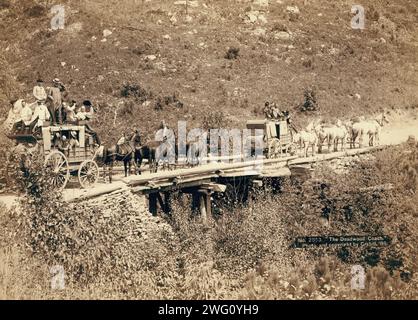 The Deadwood Coach, 1889. Two stagecoaches crossing a bridge; men in wagons are waving or tipping their hats to the photographer. Stock Photo