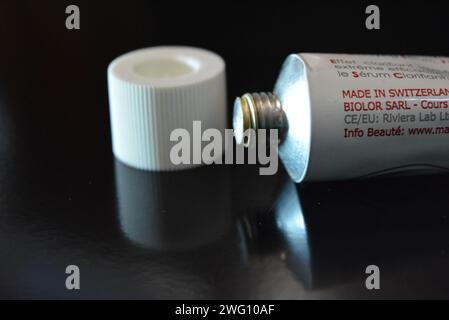 Cosmetics, white anti-inflammation cream in a white metal tube placed on a black glossy background. Stock Photo
