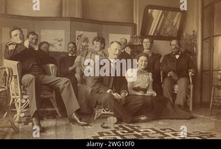 A social gathering in the veranda room, Dom Smith, Vladivostok, Russia, 1899. Group portrait shows people described in Eleanor Pray's letter of July 14, 1899. Left to right: David Clarkson, Mr. Johns (of Chicago), Mrs. Sarah Smith, Mr. Bell, Mrs. Bunker, Mr. Bunker (of San Francisco), Mrs. Johns, and William Davidson; with Mr. Miller (center front) and Eleanor Pray (right front). David Clarkson's photograph of this occasion is no. 29 in the album. Stock Photo