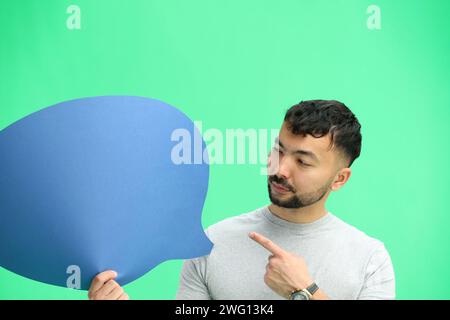 Man, on a green background, close-up, with a blue comment sign Stock Photo