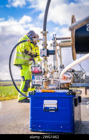 Worker in protective equipment operates outdoor machine with hoses and metal parts, glass fibre construction, Nagold, Black Forest, Germany Stock Photo