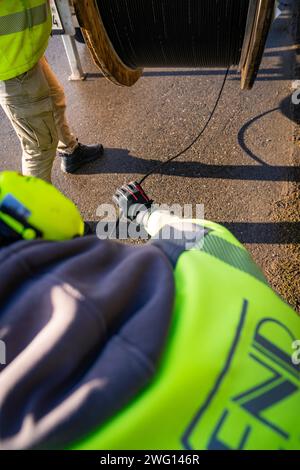 View over the shoulder of a worker in protective clothing during cable installation, fibre optic construction, Nagold, Black Forest, Germany Stock Photo