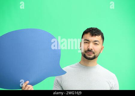 Man, on a green background, close-up, with a blue comment sign Stock Photo