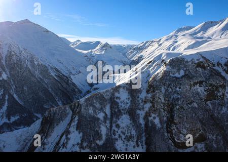 Sun lights on mountain peaks. Frozen winter weather in Caucasus. Rocks with trees seem calm and beauty Stock Photo