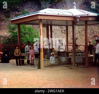 Evgenievsky spring, Borzhom, between 1905 and 1915. Group of people standing near natural spring at a health resort (in Borjomi, Georgia); some are drinking the water. Stock Photo