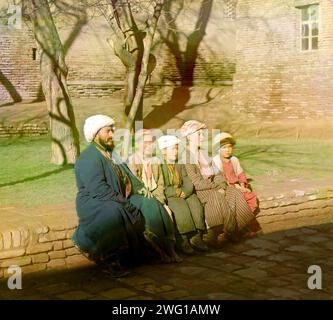 Sart schoolchildren, Samarkand, between 1905 and 1915. Man and four children seated on courtyard wall.  Russian chemist and photographer Sergey Prokudin-Gorsky (1863-1944) was a pioneer in colour photography which he used to document early 20th-century Russia and her empire, including the vanishing way of life of tribal peoples along the Silk Route in Central Asia. In a railway-carriage darkroom provided by Czar Nicholas II, Prokudin-Gorsky used the three-colour photography process to record traditional costumes and occupations, churches and mosques - many now Unesco World Heritage sites - as Stock Photo