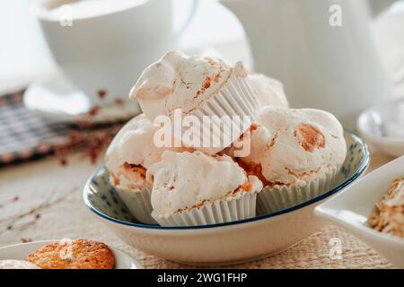 some merengues almendrados, spanish baked meringues with almonds, served in a ceramic bowl placed on a table set with a brown tablecloth Stock Photo