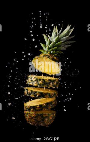 fresh and sliced pineapple with juice splashes on black background Stock Photo