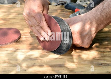 The carpenter prepares the drill for work, he attaches an emery wheel to the drill. Stock Photo