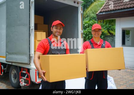 Two male delivery professionals as they hold parcels, ready to deliver them to customers at their doorstep Stock Photo