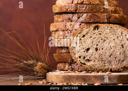 in the foreground slices of wholemeal bread with seeds and cereals and ears of wheat Stock Photo