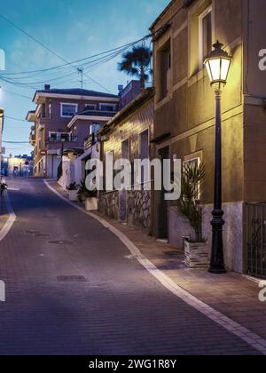 San Miguel de Salinas, Alicante - Spain. A street in San Miguel de Salinas, lit by a streetlight at sunset on a January evening. Stock Photo