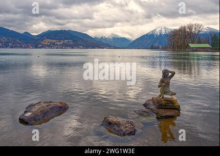 Sculpture in the shallow water of the lake and the hight mountains under the cloudy sky Stock Photo