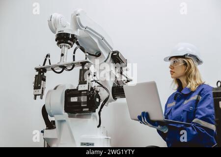 Engineer women university student learn control operate and program industry robot arm with laptop computer in robotics engineers lab classroom in pol Stock Photo