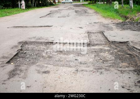 Pit repair. Damaged asphalt road with potholes. Bad road. Bad asphalt, broken highway, cracks, pits, potholes in asphalt. Stock Photo