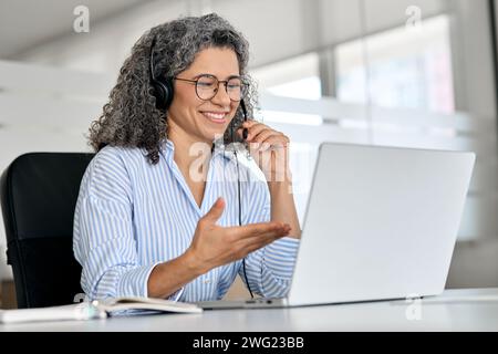 Happy mature woman call centre support agent working using laptop in office. Stock Photo