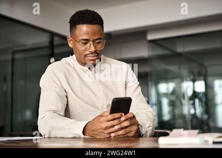 Busy African American entrepreneur using cell phone working in office. Stock Photo