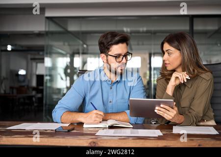 Busy professional colleagues working with digital tablet talking in office. Stock Photo