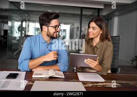 Happy professional business people working in office with tablet and talking. Stock Photo