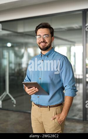 Smiling young business man manager with tab standing in office. Portrait. Stock Photo