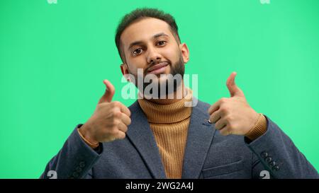 A man, close-up, on a green background, shows his thumbs up Stock Photo