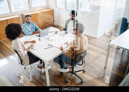 Top view of collaborative meeting shows diverse team engaging in strategic discussion at an office table, illustrating a dynamic brainstorming session. A business meeting with a group of professionals Stock Photo