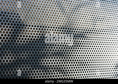 Metal mesh, background, with round identical holes, metal structure with shadow and light. Stock Photo