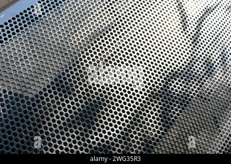 Metal mesh, background, with round identical holes, metal structure with shadow and light. Stock Photo