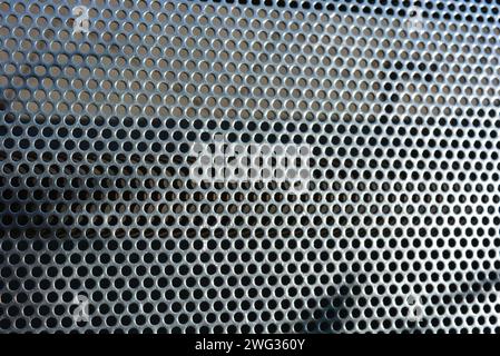 Metal mesh, background, with round identical holes, metal structure with shadow and light. Stock Photo