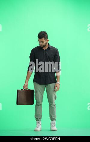 A man, on a green background, in full height, with a briefcase Stock Photo