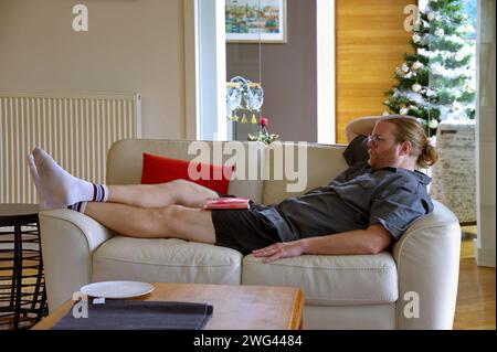 Young handsome man lying on the sofa and looking away Stock Photo