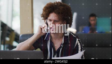 Young biracial man talks on the phone in an office Stock Photo
