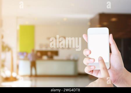 woman hand hold mobile smartphone with hotel lobby blur background, hotel reception Stock Photo