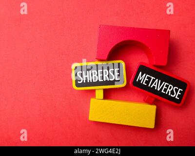 Top view colored block and wooden board with text SHIBERSE METAVERSE on red background. Stock Photo