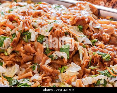 Fried, wide rice noodles and cabbage, cale and carrots at market in Thailand. Shallow depth of field. Stock Photo