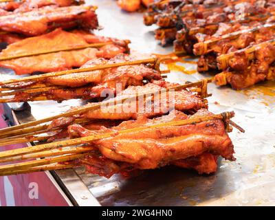 Chciken barbecued between two bamboo sticks at a market in Thailand. Shallow depth of field. Stock Photo