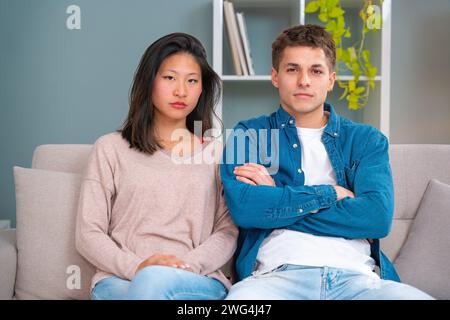 Portrait of young serious multiethnic couple using smartphone technology.Indoors Stock Photo