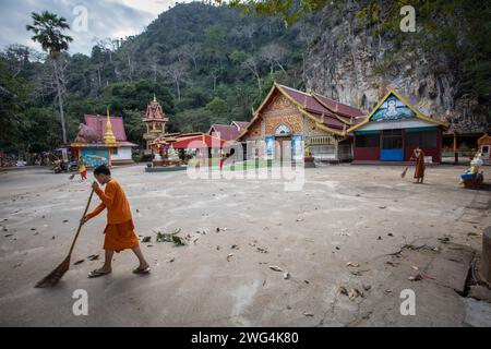 Young monks clean up the floor of the Wat Tham Pla Temple. Wat Tham Pla (Cave Fish Temple) is also referred to as the 'Monkey Temple' for Thai locals, located 16 kilometers from Mae Sai, the northernmost city of Thailand. Stock Photo