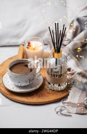 Bamboo sticks in bottle with scented candles and cup of coffee on the bed. Cozy atmosphere concept. Stock Photo