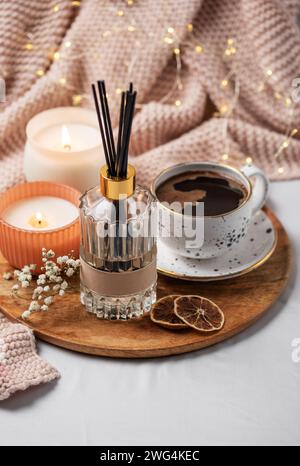 Bamboo sticks in bottle with scented candles and cup of coffee on the bed. Cozy atmosphere concept. Stock Photo