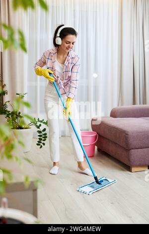 Woman, singing and dancing while cleaning living room for fun domestic ...
